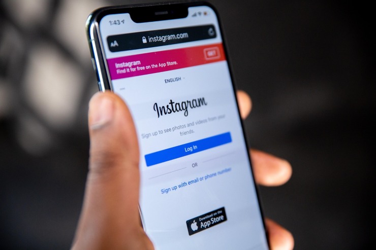 persona con in mano un cellulare e sullo schermo Instagram